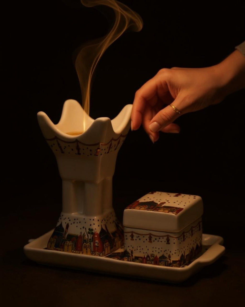 ZYVORA Mabkhara — placing bakhoor onto the warm cradle. Smoke threads through the room.